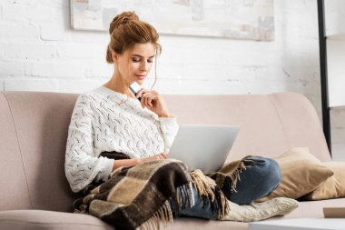 beyaz kazak kredi ve dizüstü bilgisayar tutan çekici kadın