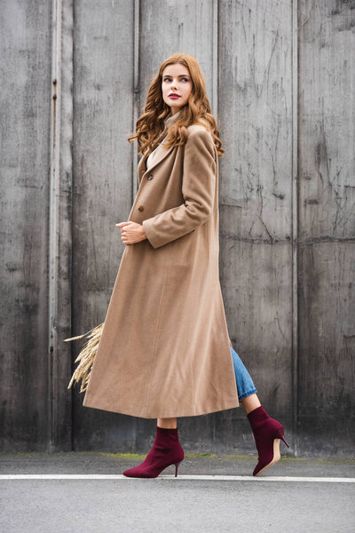 attractive woman in coat holding spikes and looking away 