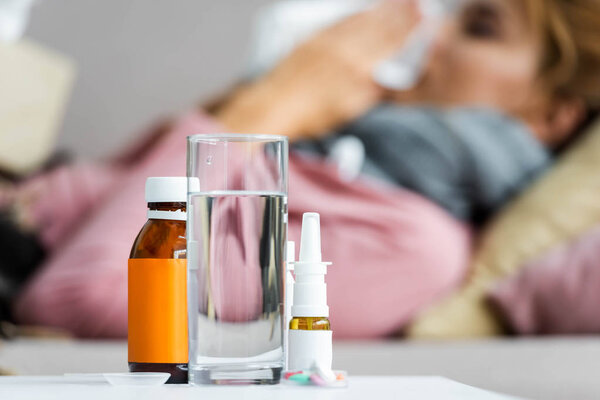 selective focus of nose drops, cough syrup and glass of water 
