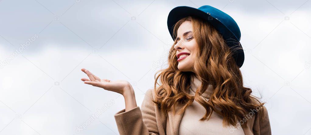 panoramic shot of attractive and smiling woman in blue hat with closed eyes 