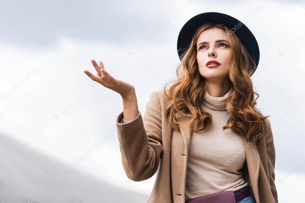 attractive woman in blue hat and coat looking up 