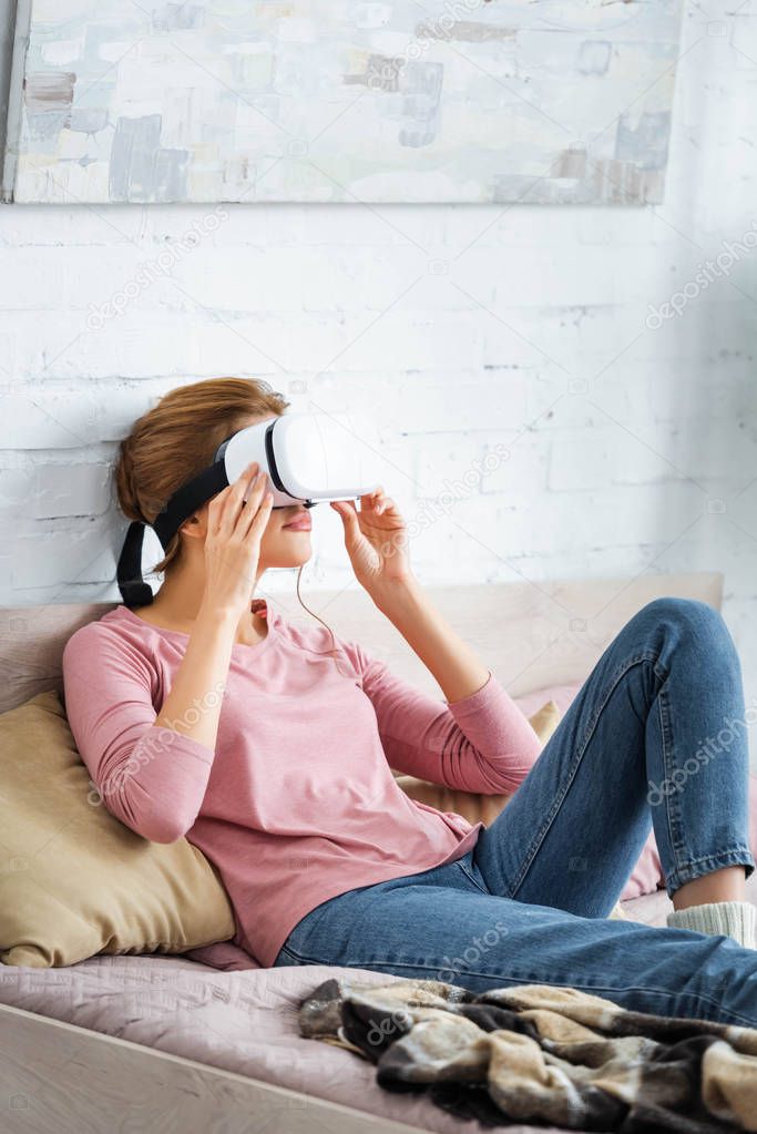 young adult woman playing with virtual reality headset in apartment 