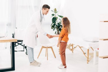 beyaz önlük ve çocuk el sıkışma ve birbirlerine bakarak pediatrist tam uzunlukta görünümü