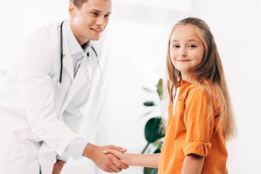 beyaz önlük ve çocuk el sıkışma ve birbirlerine bakarak pediatrist