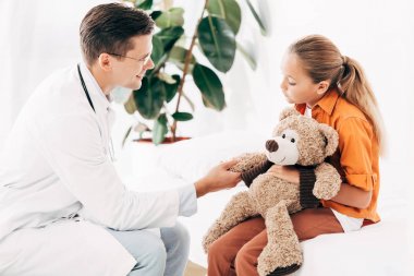 Beyaz önlük ve çocuk klinikte oyuncak ayı ile pediatrist