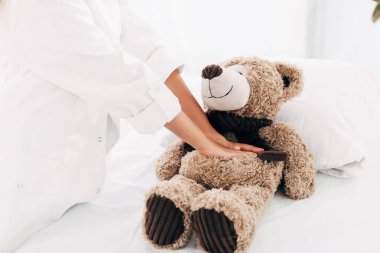 doktor kostümlü çocuğun oyuncak ayıya kalp masajı yapması kısmi görünümü