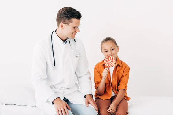 Smiling Pediatrist White Coat Child Lollipop Sitting Hospital Bed Clinic — Stock Photo, Image