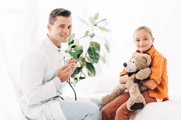 Pediatra Sorridente Cappotto Bianco Bambino Con Orsacchiotto Clinica — Foto Stock