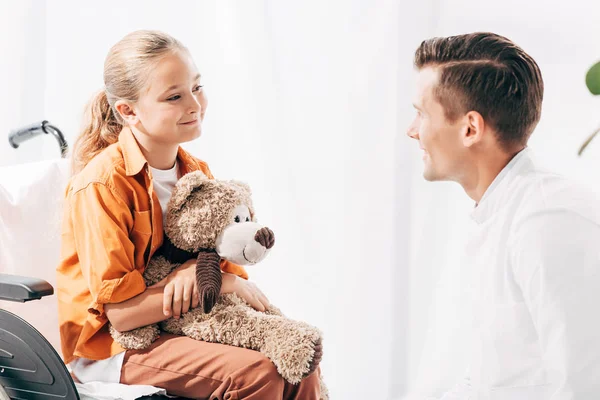 Barnläkare Och Barn Med Teddybjörn Rullstol Tittar Varandra — Stockfoto