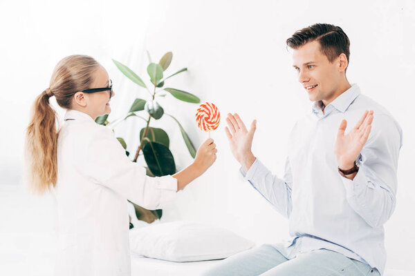 child in doctor costume giving patient candy in clinic