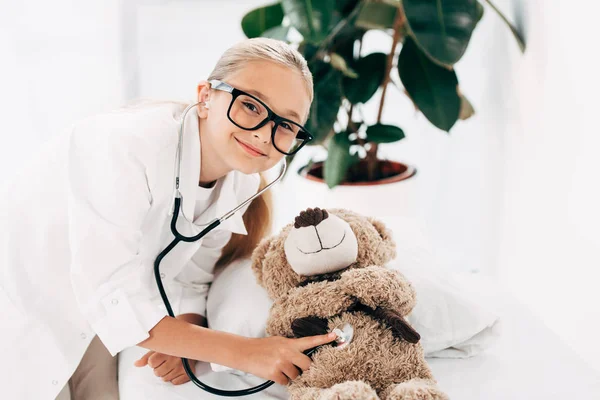 Niño Sonriente Traje Médico Examinando Osito Peluche Con Estetoscopio — Foto de Stock