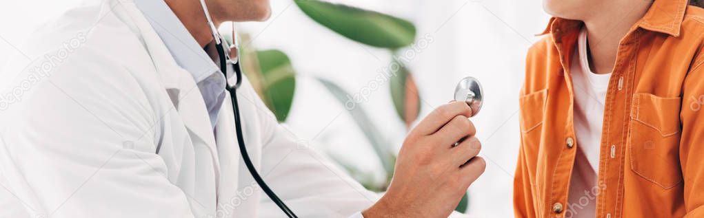 panoramic shot of pediatrist in white coat examining kid with stethoscope