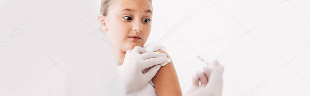panoramic shot of pediatrist in latex gloves doing injection to child isolated on white