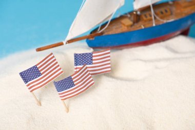Mavi üzerine izole minyatür gemi yakınında beyaz kum amerikan ulusal bayrakları