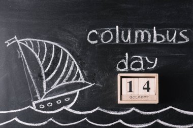 wooden calendar with October 14 date on chalkboard with ship drawing and Columbus Day inscription  clipart