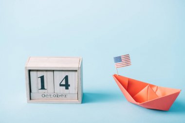 mavi arka plan üzerinde Amerikan bayrağı ile kırmızı kağıt domuz yakın 14 Ekim tarih ile ahşap takvim 