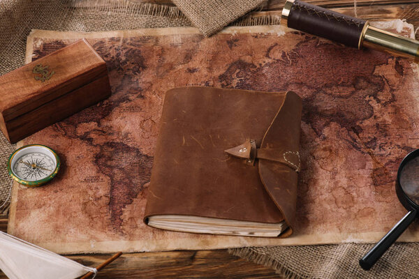 brown leather notebook on wooden table with world map and sacking
