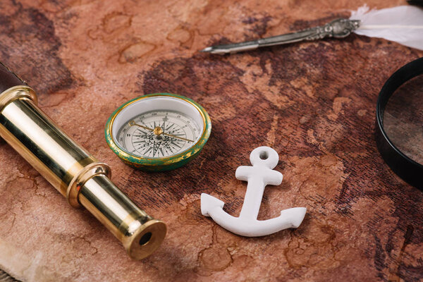 compass, white anchor, nib and telescope on world map