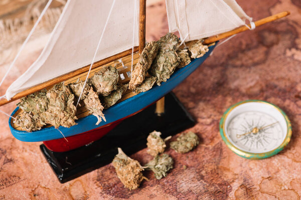 декоративный корабль с сухими кусками растений рядом с компасом на карте старого мира
