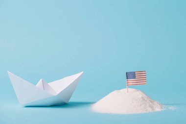 mavi arka plan üzerinde beyaz kum Amerikan ulusal bayrağı yakınında kağıt tekne