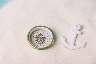 compass and plastic anchor on white sand clipart