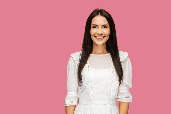 happy girl smiling while looking at camera isolated on pink 