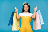 šťastná mladá žena s barevnou nákupní taškami izolovaná na modré 