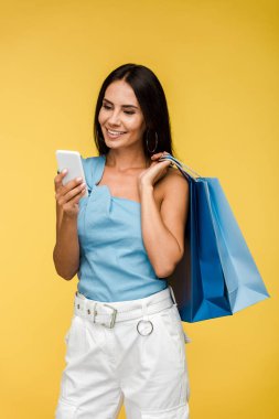 turuncu izole akıllı telefon bakarak neşeli genç kadın