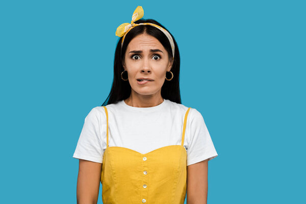 stressful young woman in headband isolated on blue 