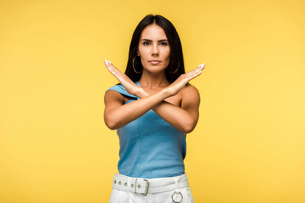 attractive woman showing stop sign with hands isolated on orange 