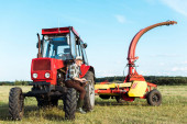 Landwirt mit digitalem Tablet in der Nähe eines roten Traktors 