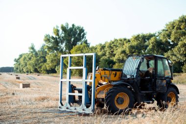 selective focus of modern tractor on wheat field near trees  clipart