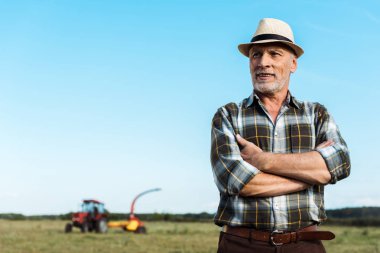 bearded senior farmer standing with crossed arms in field  clipart