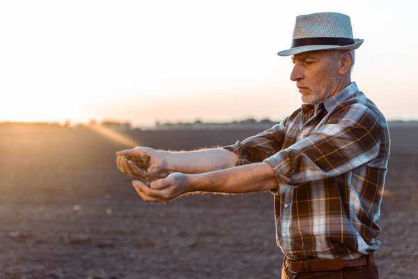 самозанятый фермер в соломенной шляпе, сеющий семена вечером
 