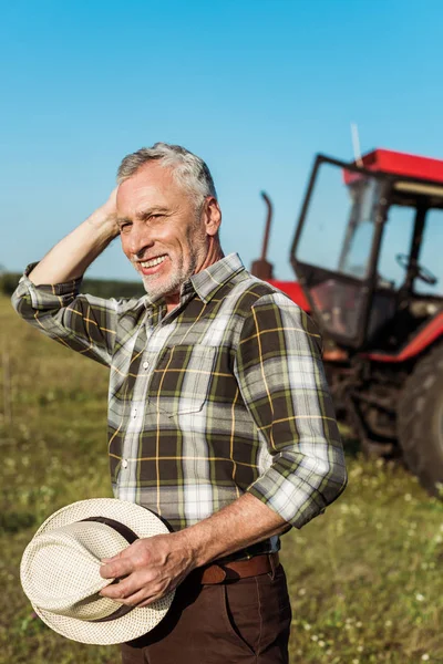 Šťastný Samostatně Výdělečně Daný Zemědělec Držící Slaměný Klobouk Blízkosti Traktoru — Stock fotografie