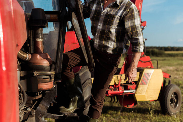 selective focus of self-employed farmer standing near modern tractor 