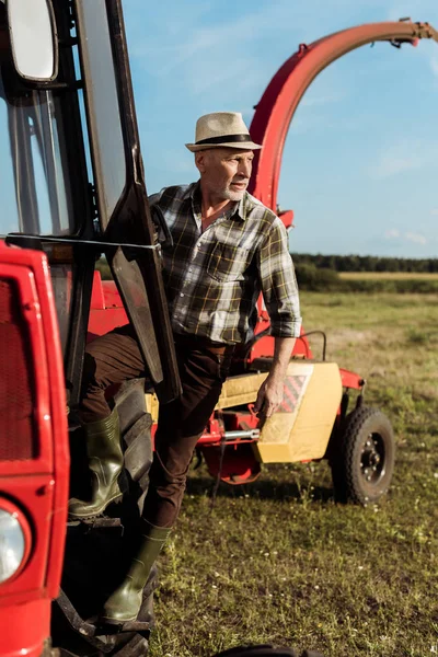 selective focus of senior farmer near modern tractor