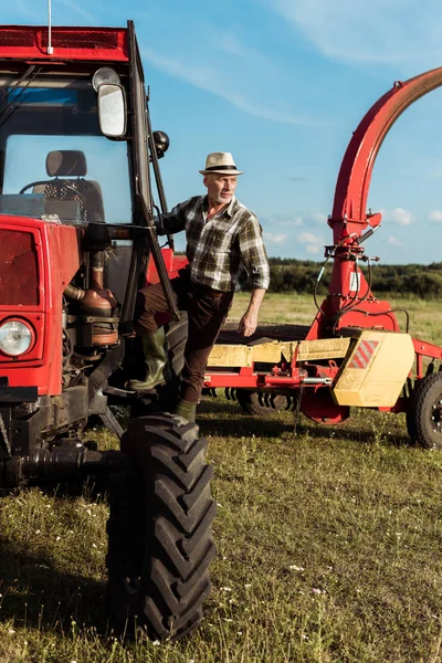 現代のトラクターの近くに自営業のシニア農家 — ストック写真
