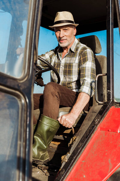 selective focus of self-employed senior man driving tractor 
