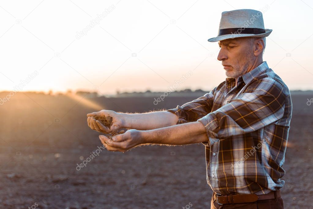 self-employed farmer in straw hat sowing seeds in evening 