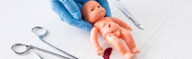 tıbbi aletlerin yanında kan ile bebek bebek tutan mavi lateks eldiven doktor panoramik atış 