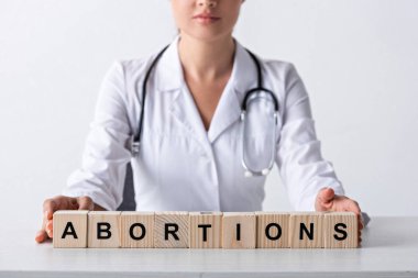 cropped view of doctor touching cubes with abortion letters  clipart