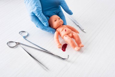 tıbbi aletlerin yanında kan ile bebek bebek tutan mavi lateks eldiven doktor kırpılmış görünümü 