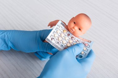 elinde kürtaj hapları ve bebek bebek tutan lateks eldiven doktor kırpılmış görünümü 