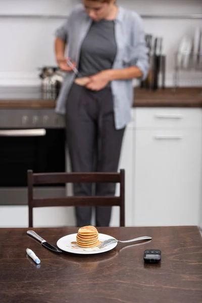 医療機器の近くにおいしいパンケーキの選択的な焦点と台所の女性 — ストック写真