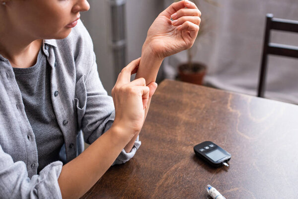 cropped view of woman checking pulse near table 
