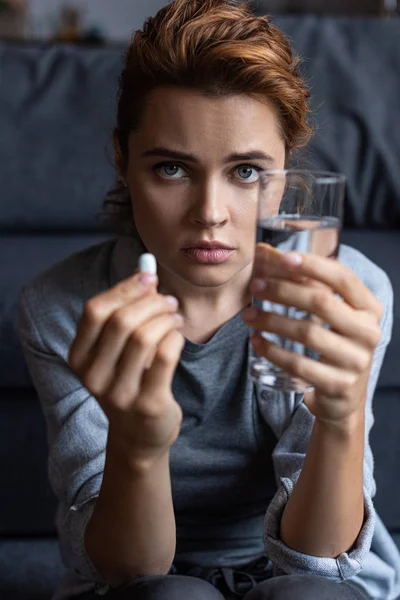 錠剤と水のガラスを保持する病気の女性の選択的な焦点 — ストック写真