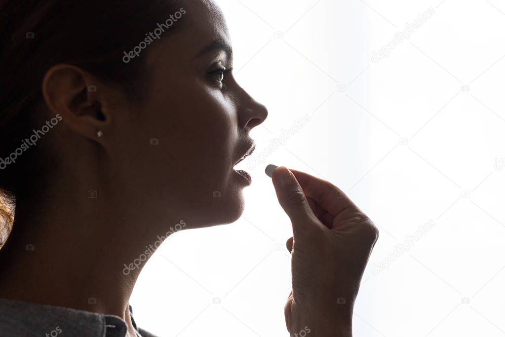 side view of beautiful woman taking pill at home 