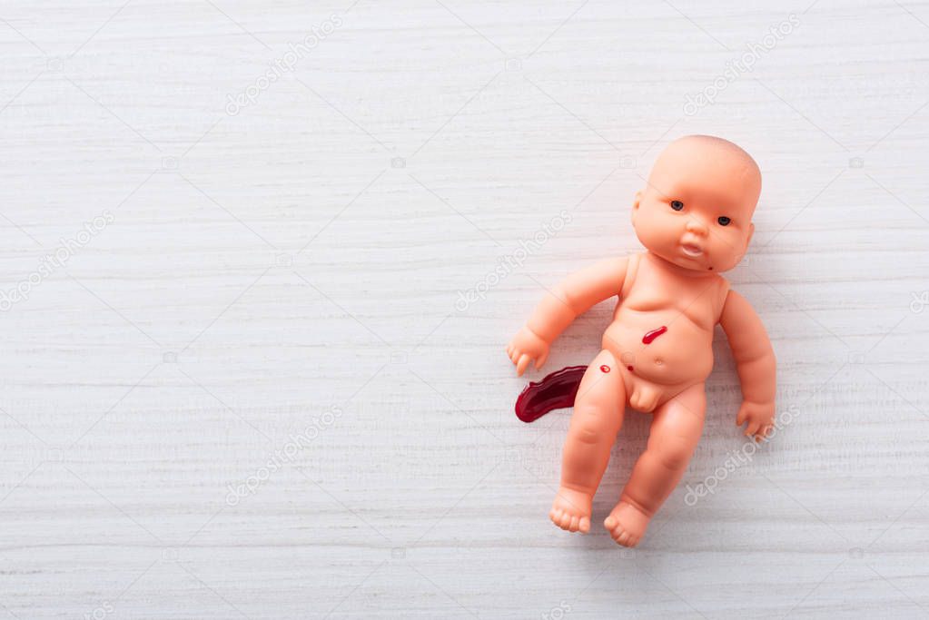 top view of injured baby doll with blood on table 