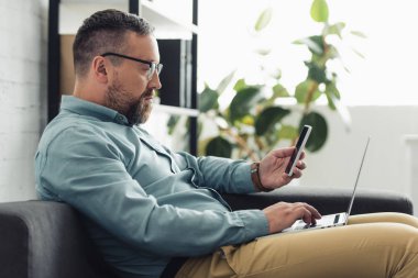 dizüstü bilgisayar ve akıllı telefon tutan gömlek yakışıklı işadamıyan görünümü 